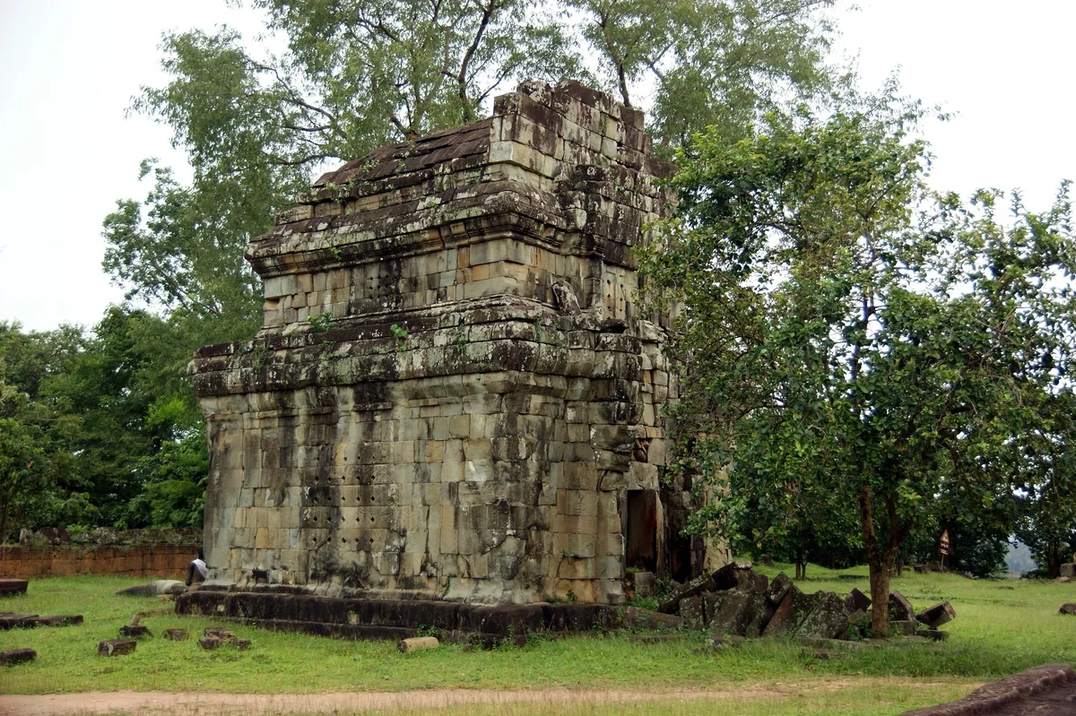 A weathered stone tower of Phnom Bakheng temple stands amid green trees near Siem Reap.