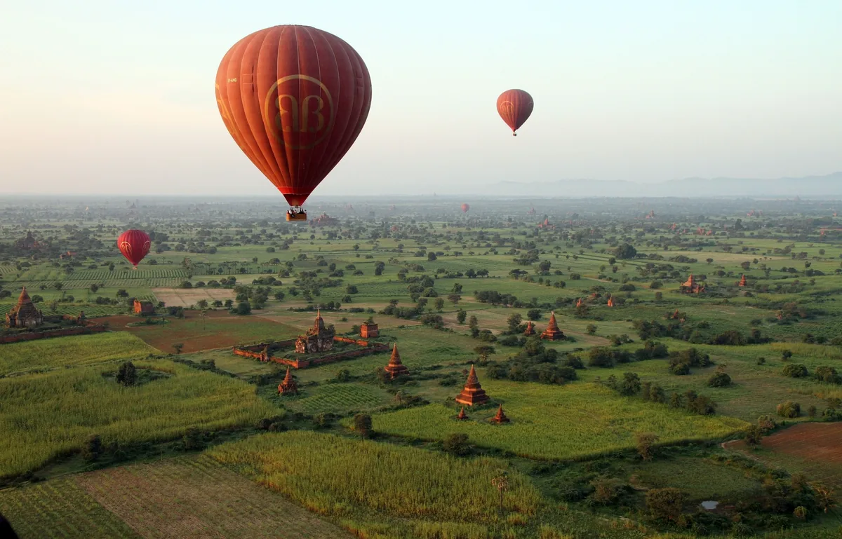 Hot air balloons drift over the temple-studded plains of Bagan at dawn.