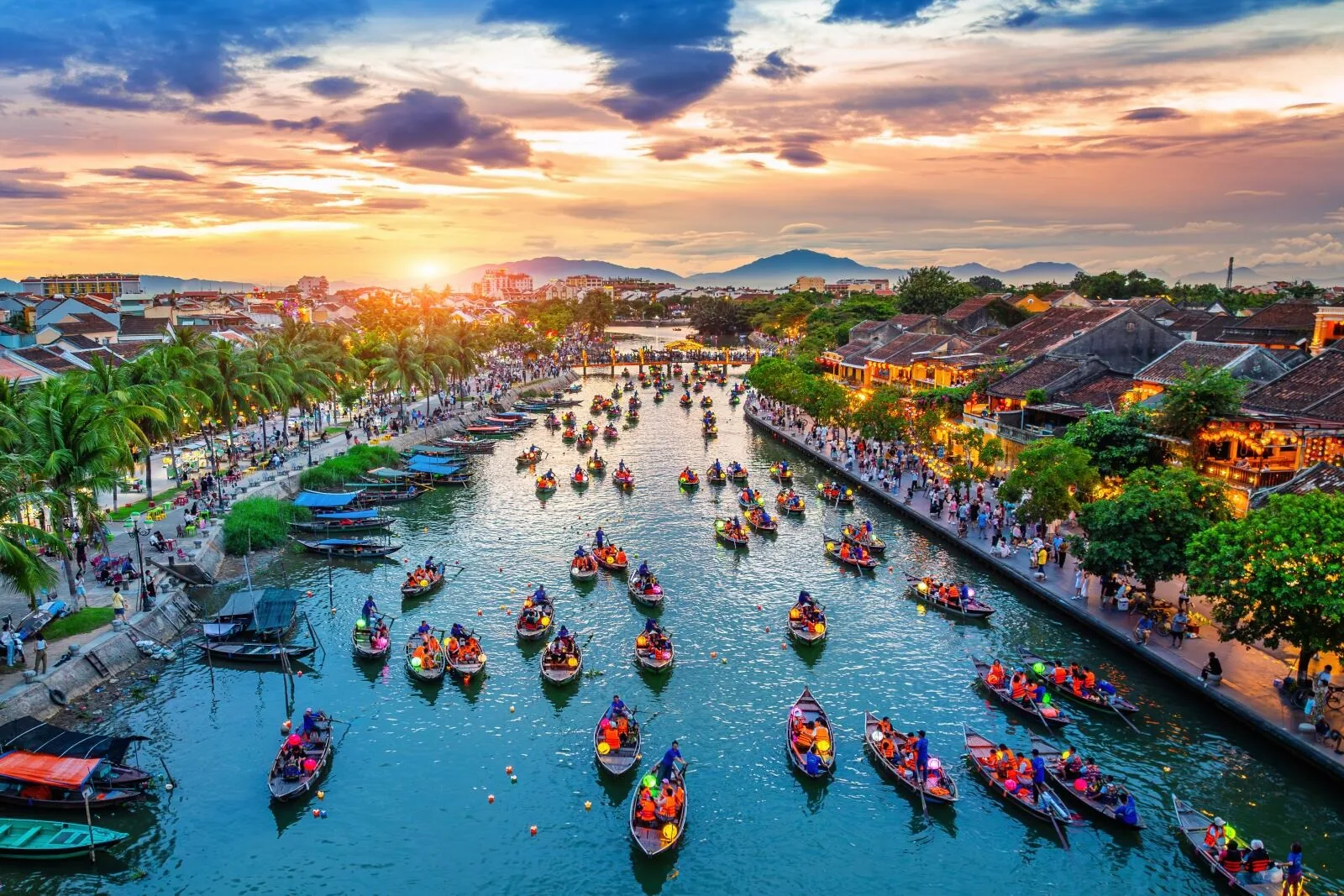Dozens of lantern boats fill the Thu Bon River at sunset in Hoi An's ancient town.