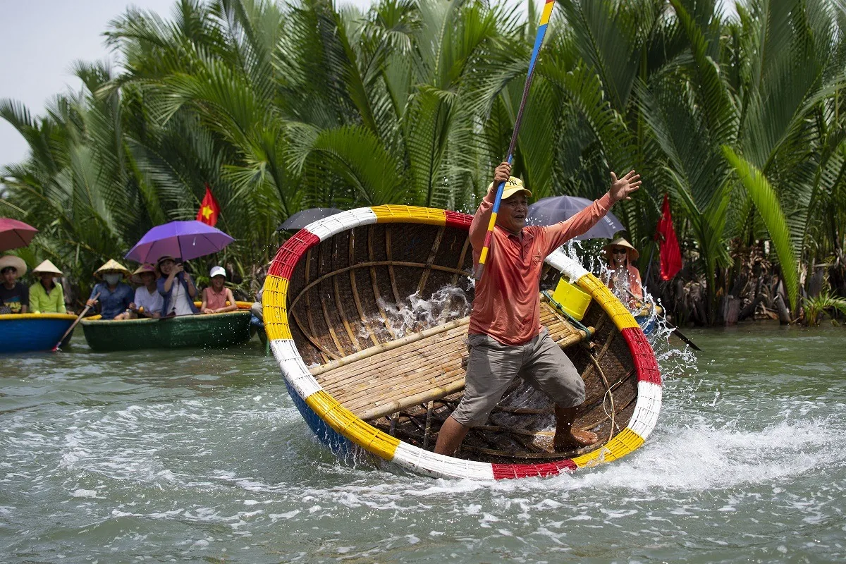 A boatman spins a colorful basket boat through water at the Cam Thanh coconut village near Hoi An.