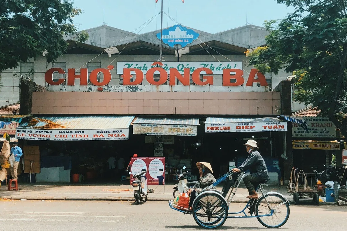 A cyclo driver pedals a passenger past the entrance of Dong Ba Market in Hue.