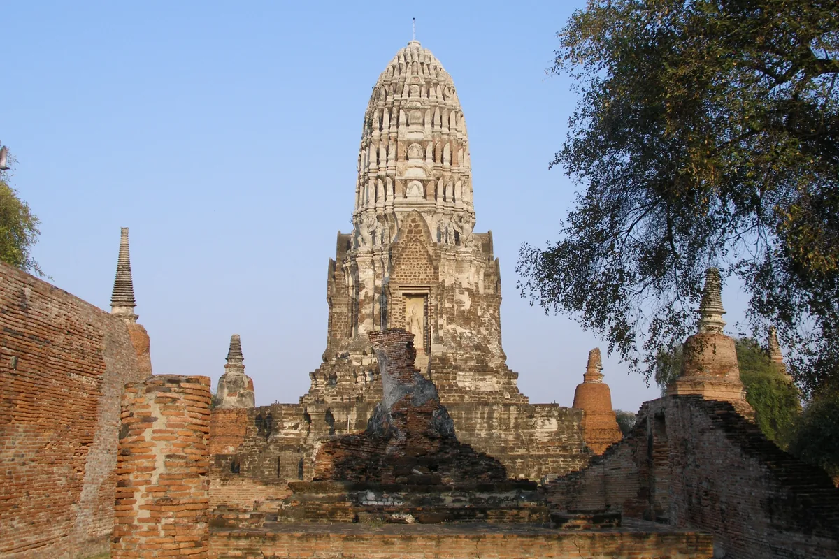 The tall corncob-style prang of Wat Phra Ram rises above ancient brick ruins in Ayutthaya, Thailand.