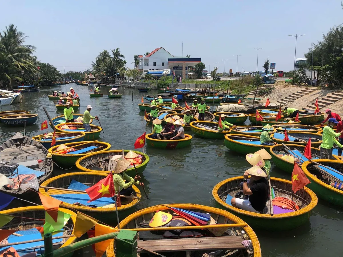 Rows of round bamboo basket boats with rowers in green shirts crowd a canal in Cam Thanh, Hoi An.