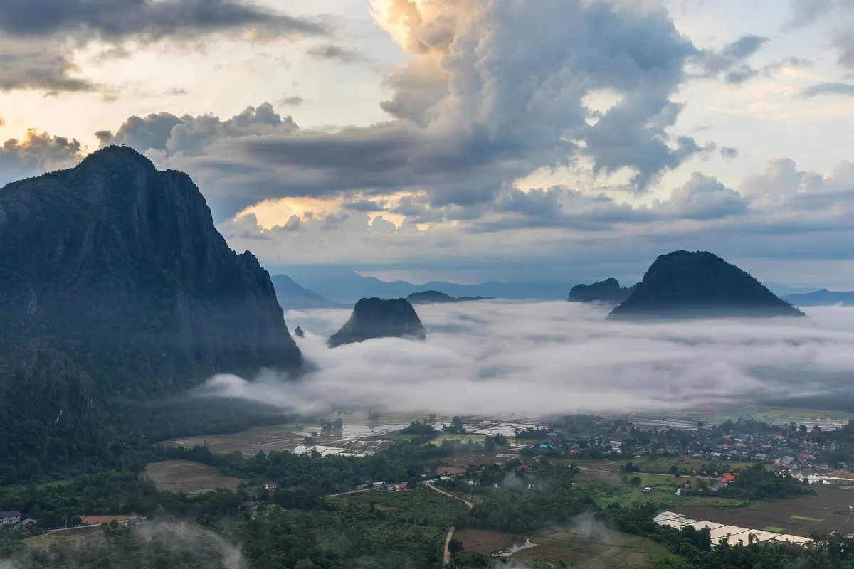 Karst peaks rise above a sea of clouds at sunrise over Vang Vieng's valley