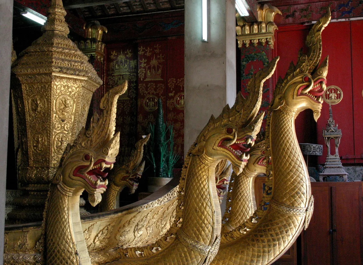 Golden multi-headed naga serpent carvings adorn a royal funeral carriage inside Wat Xieng Thong in Luang Prabang.