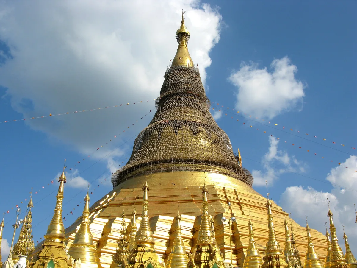 The golden bell-shaped stupa of Shwedagon Pagoda rises against a blue sky in Yangon.