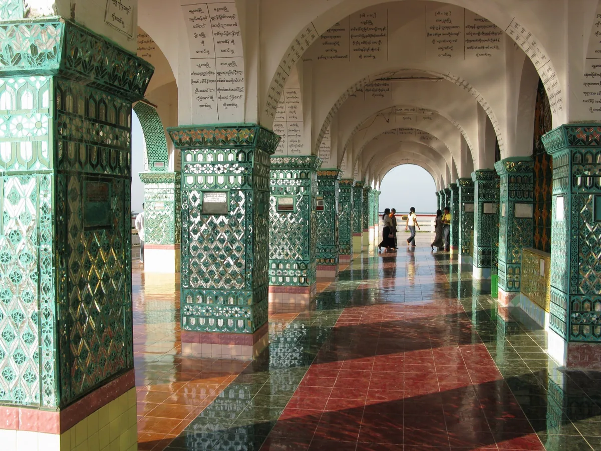 Mosaic-tiled columns line a covered arched walkway at Sutaungpyei Pagoda on Mandalay Hill.
