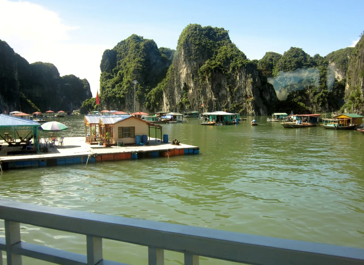 A floating fishing village with colorful houses sits among limestone karsts in Ha Long Bay, Vietnam.
