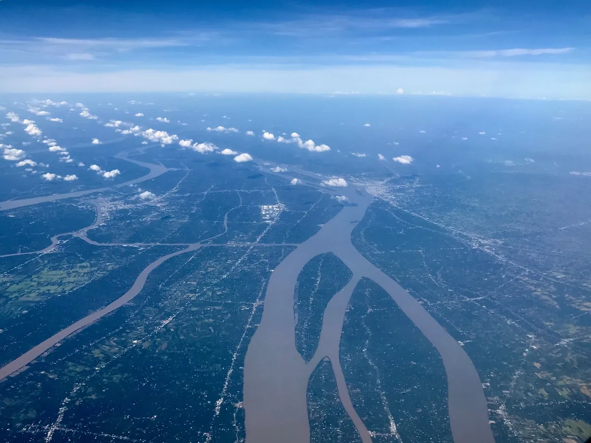 Aerial view of the Mekong River branching into muddy channels across the delta's patchwork farmland