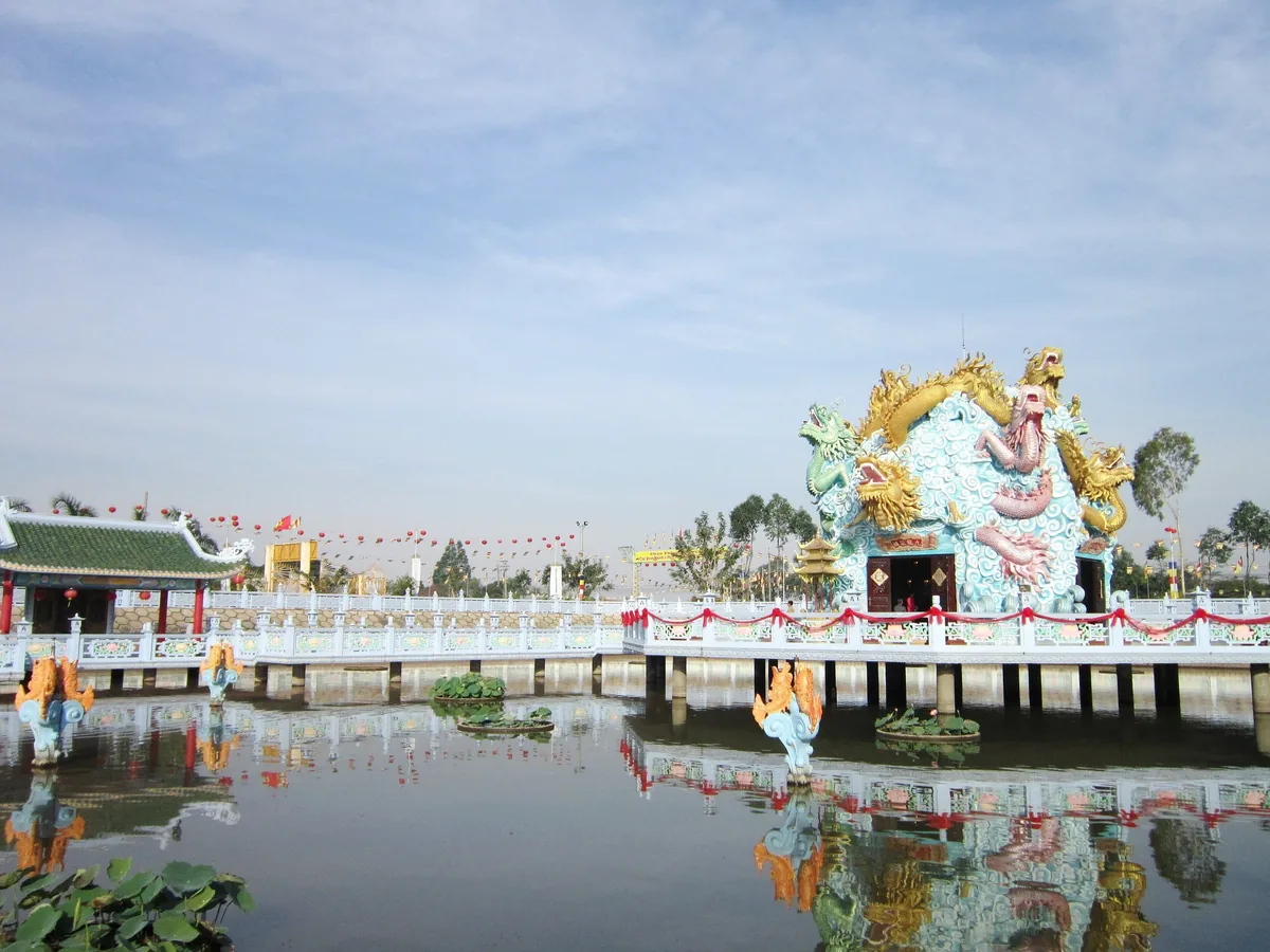 An elaborate dragon-shaped temple structure sits over a pond on a bridge in Chau Doc.