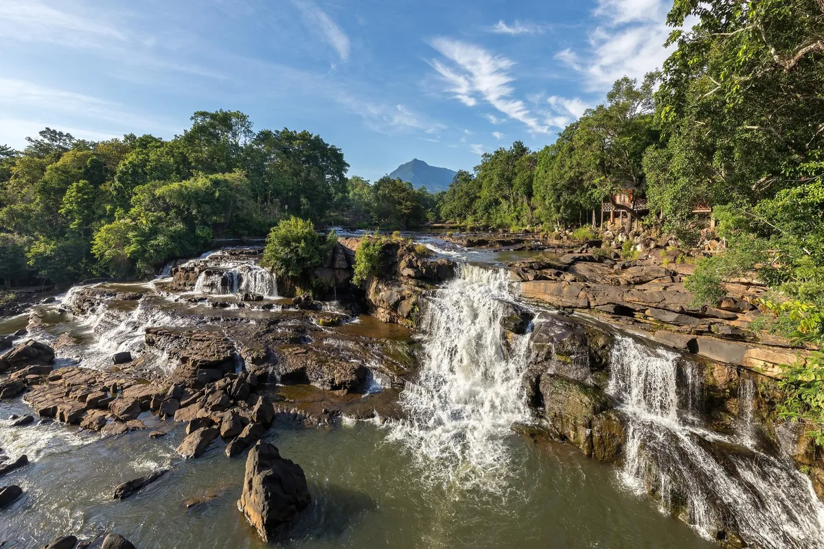 Wide waterfalls cascade over rocky terraces near Tad Lo village on the Bolaven Plateau in Laos.