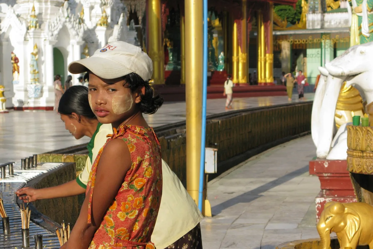 A girl with thanaka on her face pauses near candle stands at Shwedagon Pagoda in Yangon.
