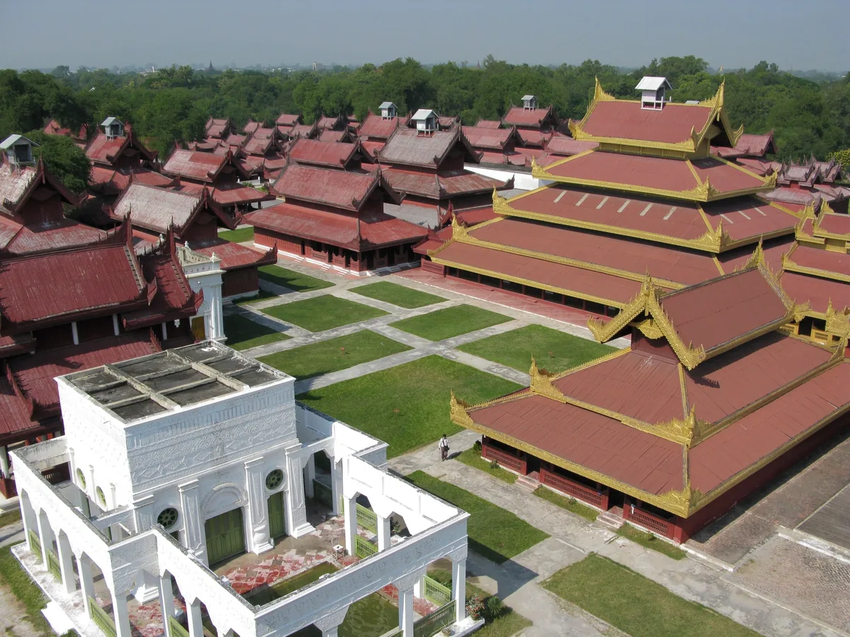 Aerial view of Mandalay Palace's tiered red and gold pavilion roofs and manicured lawns in Mandalay, Myanmar.
